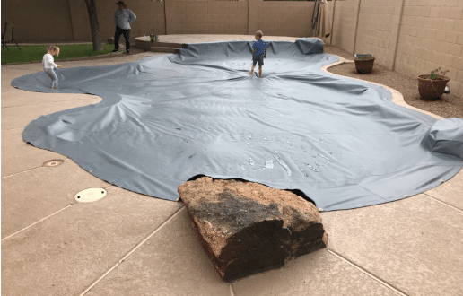 Children safely on top of a charcoal gray PowerLock solar safety cover