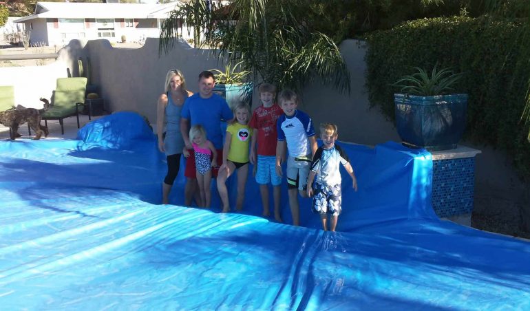 Arizona family standing on blue PowerLock safety pool cover by Solar Safe Pool Covers